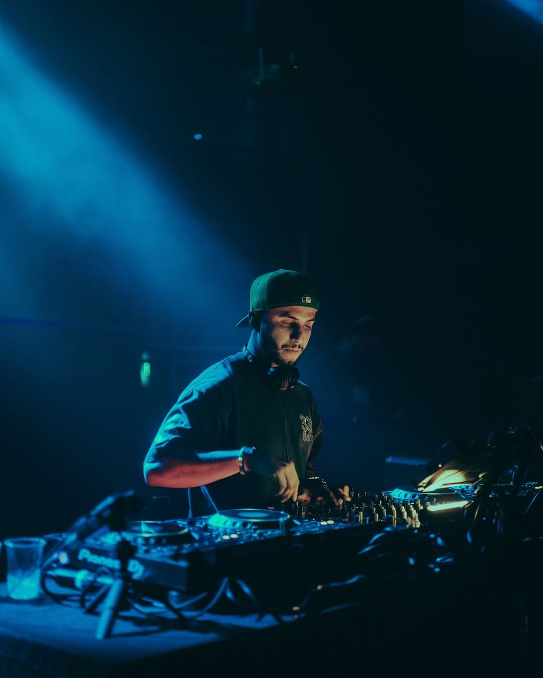 A DJ playing under deep blue light